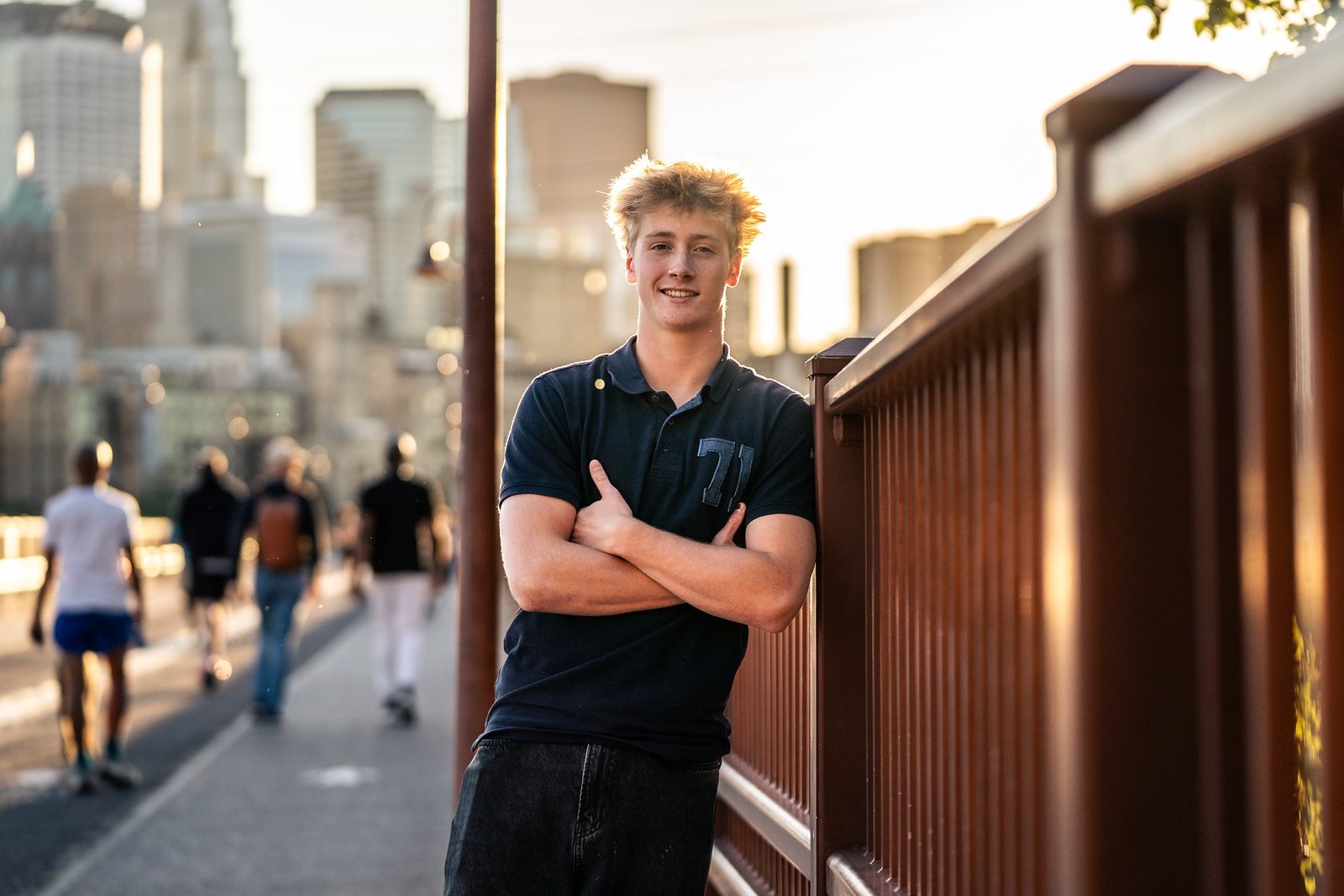 Senior portrait leaning on a railing with the city skyline behind