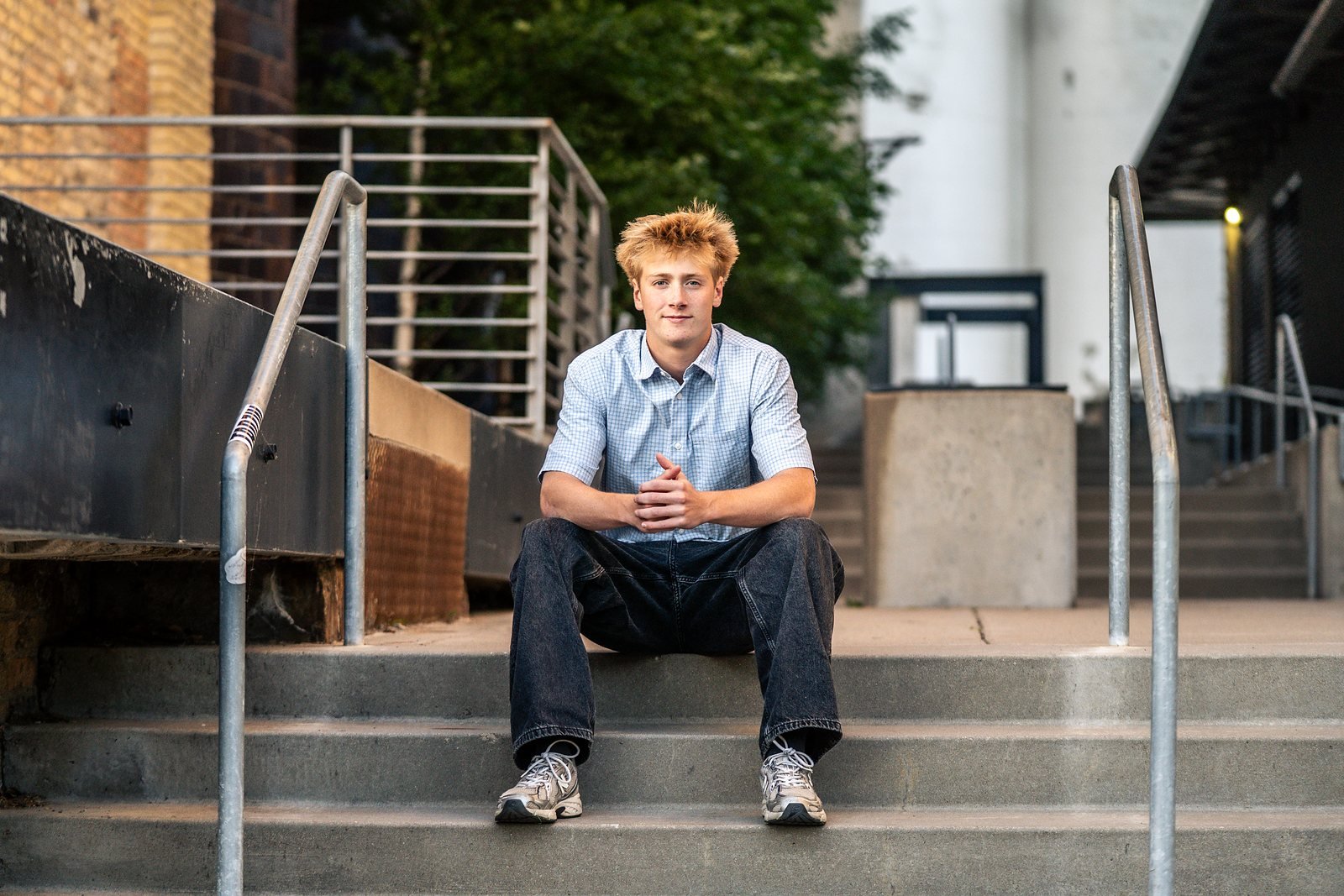 Senior portrait sitting on concrete steps between railings